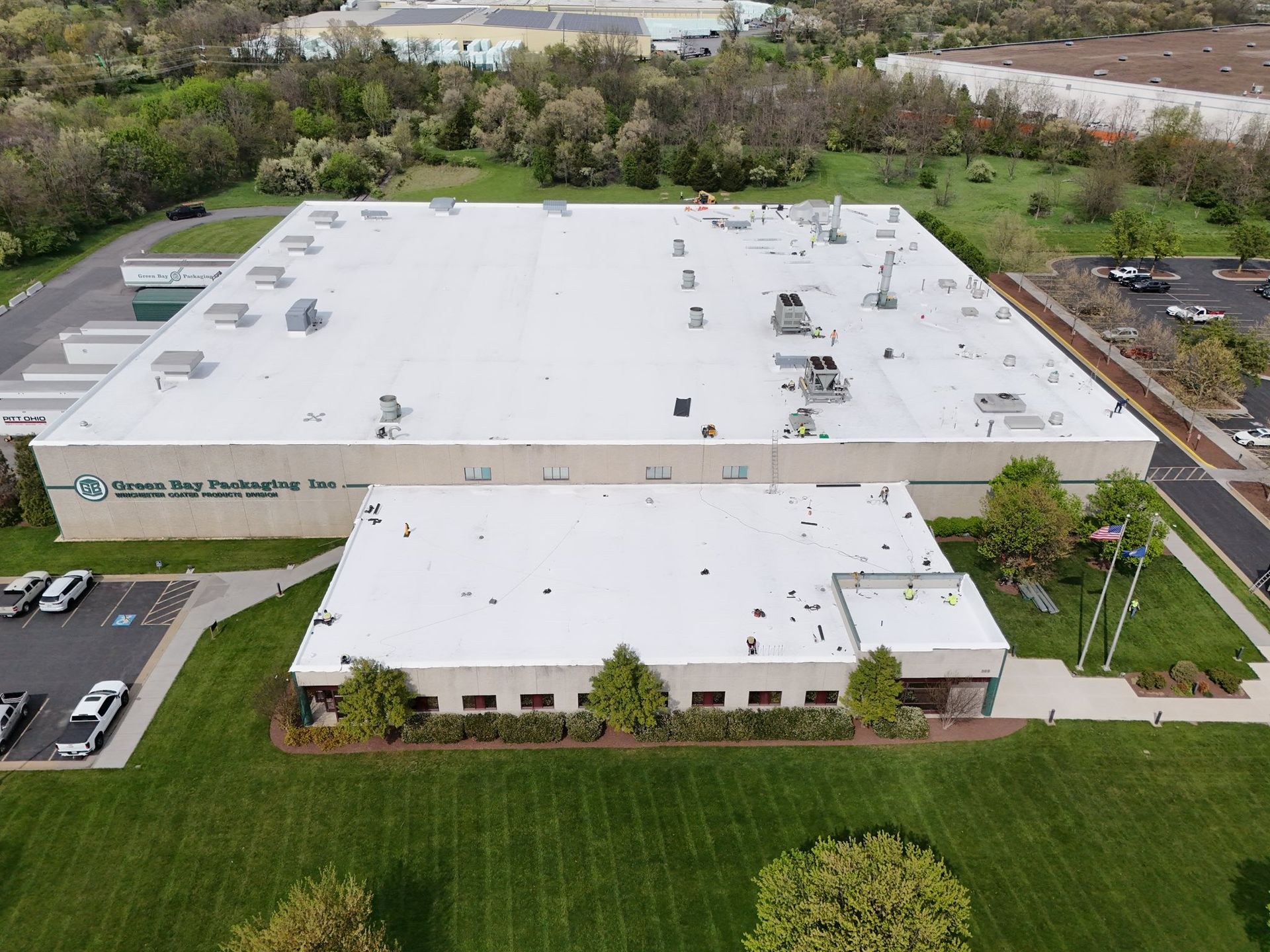 Aerial view of a finished white single ply membrane roof covering a large warehouse and attached office building with rooftop HVAC units and clean parapet edges, completed commercial roof replacement by Black Stone Roofing of Martinsburg WV