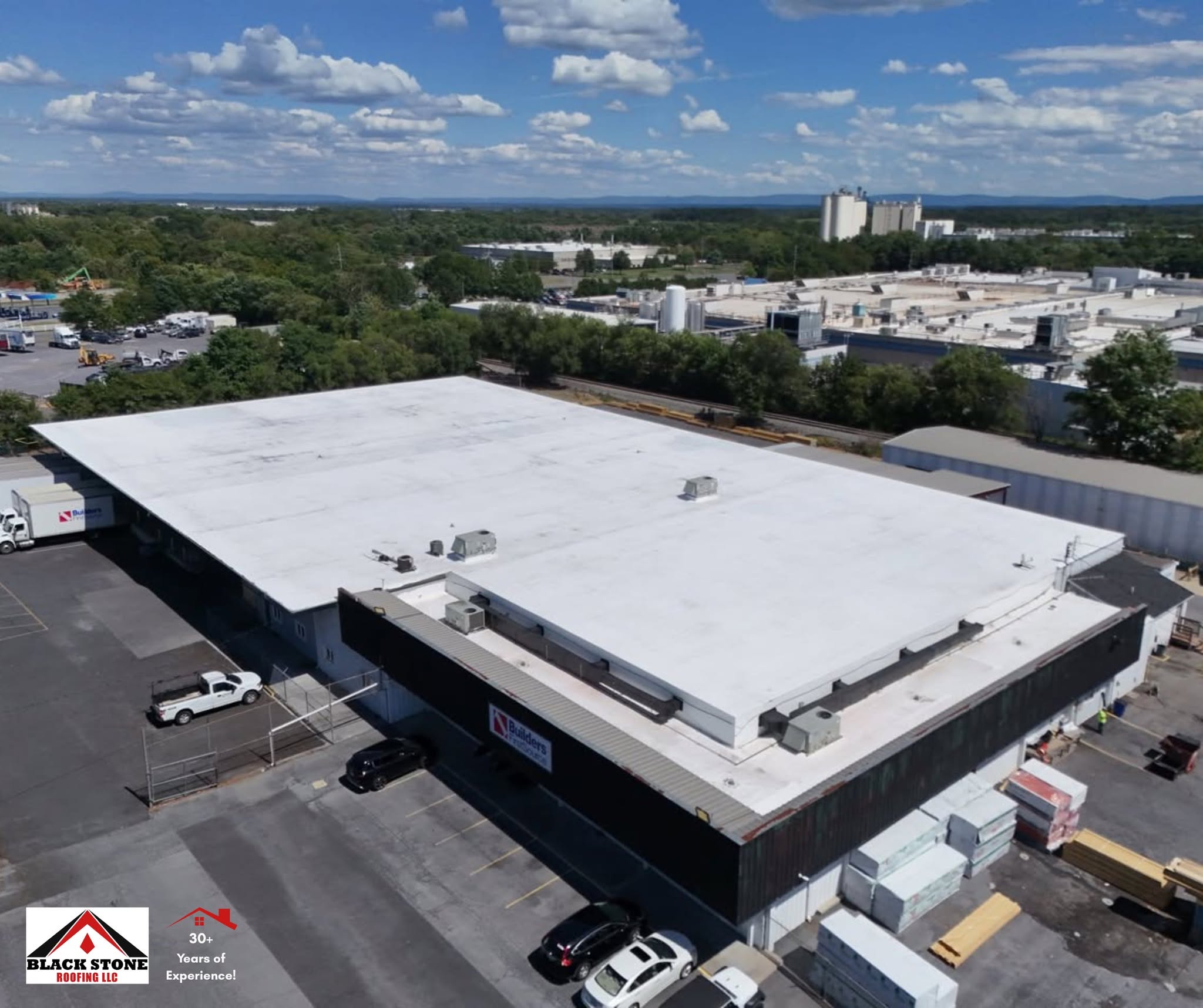 Aerial view of a completed white TPO membrane warehouse roof by Black Stone Roofing